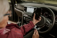 Senior woman driving, using GPS on smartphone