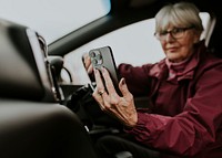 Senior woman driving, using GPS on smartphone