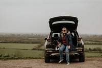 Woman and dog sitting at the back of her car