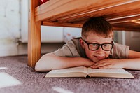 Boy reading book under his bed