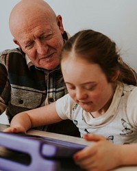 Girl with Down Syndrome playing game on tablet