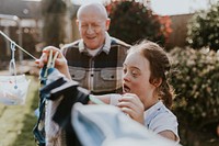 Girl with Down Syndrome hanging laundry with her dad