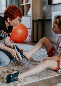 Mum putting shoes for daughter, down syndrome awareness