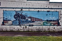                         A weathered mural, fittingly on a wall across from the train depot, showing an old-time steam locomotive-driven Florida West Coast Line train in Trenton, a small city in central Florida                        