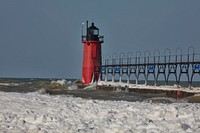                         Since 1871, a South Haven Light has guarded the entrance to the Black River on Lake Michigan in South Haven, Michigan. The first was made of wood. It was replaced by this steel lighthouse, brightly painted red, in 1903. Ten years later, its pier was extended to 700' feel, and an 800-foot steel catwalk was installed. In 1940, both were lengthened to 1,200 feet                        
