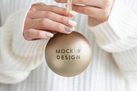 Woman in a white sweater holding a gold bauble mockup