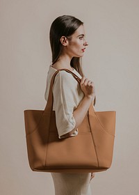 Woman holding brown leather bag, studio shoot
