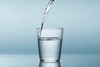 Pouring water in glass, blue background