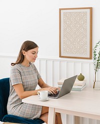 Woman sitting on a chair by a frame mockup on the white wall