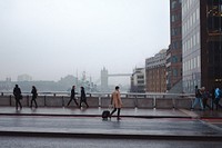 Busy people move through the city and across a bridge with London Bridge towering in the background. View public domain image source here