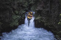 A raft full of people goes down a small waterfall into the rapids. View public domain image source here