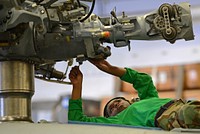 U.S. Navy Aviation Machinist's Mate 3rd Class Jhennel Myers, assigned to Helicopter Sea Combat Squadron (HSC) 25, conducts maintenance on an MH-60S Seahawk helicopter in the hangar bay of the amphibious assault ship USS Bonhomme Richard (LHD 6) in the East China Sea March 17, 2014.