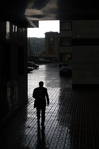 Man walking through buildings. Original public domain image from Flickr