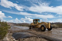 Excavator  removing debris from road after flooding