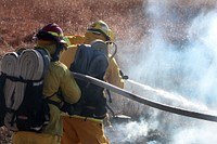 Firefighter, combating flame, water hose. Original public domain image from Flickr