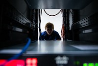 U.S. Coast Guard Chief Warrant Officer DeAnna Melleby, Information Systems Security Officer for the Coast Guard Command, Control, Communication and Information Technology unit at Coast Guard Base Boston, peers through a space in a server April 20, 2017.