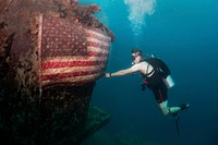 A U.S. Navy master chief petty officer assigned to Explosive Ordnance Disposal (EOD) Group 1 fixes an American flag on the American Tanker, a sunken concrete barge used to transport fuel during WWII, in Guam’s Apra Harbor June 21, 2017.