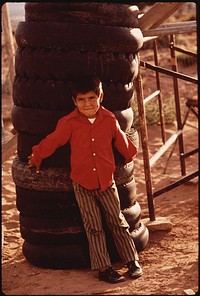 Navaho Boy Leans Against Tower of Discarded Tires. Lack of Disposal Facilities Is A Common Problem in Remote Areas of the Navaho Reservation. Photographer: Eiler, Terry. Original public domain image from Flickr