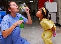 Kayla Hamrick, left, a member of Latter-day Saint Charities, blows bubbles for a child in the pediatric ward of Military Sealift Command hospital ship USNS Mercy (T-AH 19), in Sihanoukville, Cambodia, June 22, 2010.