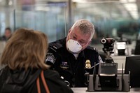 An officer with U.S. Customs and Border Protection Office of Field Operations welcomes and clears international travelers arriving at Dulles International Airport in Dulles, Va., March 13, 2020.