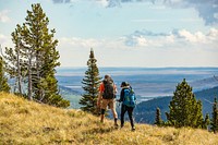 Two people walk through grass high above the plains. Original public domain image from Flickr