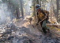 Luis Bernardo, Feather River Hot Shot, performs mop up support to ensure ground is cold during the Dixie Fire in Lassen National Forest, California. USDA Forest Service photo by Cecilio Ricardo. Original public domain image from Flickr