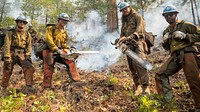 Blue Ridge and Plumas Hot Shots connect after completing a fire-suppressing fire line on a smoky steep-sloped mountain to suppress the Dixie Fire in the Lassen National Forest, California. USDA Forest Service photo by Cecilio Ricardo. Original public domain image from Flickr