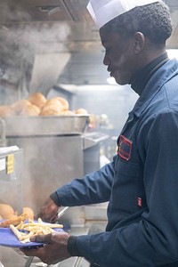 Logistics Specialist Seaman Stephane Pognon serves food aboard the Arleigh Burke-class guided-missile destroyer USS Arleigh Burke (DDG 51), November 16, 2021. Original public domain image from Flickr