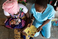 A nurse shares educational materials with mother to protect her family from malaria at Petifu Junction Health Centre, August 9, 2021. Original public domain image from Flickr