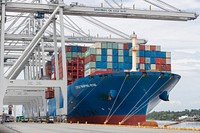 Containers are lifted off a container ship by quay cranes. Original public domain image from Flickr