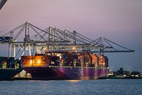 Containers are lifted off a container ship by quay cranes. Original public domain image from Flickr