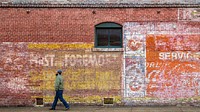 A man walks past a faded wall signage in Central Historic District and Railroad Historic District of Greenwood, MS, on January 28, 2022. USDA Media by Lance Cheung.