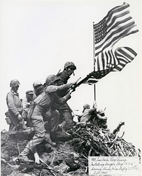 09-8254-4First flag raising atop Mount Suribachi, 02/23/1945. Sergeant Hansen (without helmet), Sergeant Thomas (seated by flagpole), Corporal Lindberg (standing at right) and Private 1st Class Michaels (on guard with carbine). Out of the 40 man platoon that made the climb up Suribachi and raised the 1st American flag on captured Japanese territory, 36 were killed or wounded in the subsequent fighting on Iwo Jima. Hospital Corpsman John Bradley participated in this. See en.wikipedia.org/wiki/John_Bradley_(United_States_Navy) for an explanation of the two flag raisings.