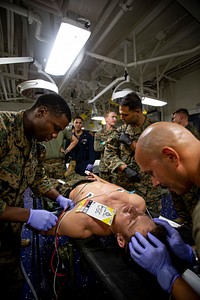 US Navy Sailors conduct a simulated mass casualty drill in response to a helicopter raid training exercise 210618-M-TS451-1669U.S. Navy sailors with America Amphibious Ready Group, 31st Marine Expeditionary Unit (MEU), check for potential trauma to a patient’s head during a mass casualty drill to assess skills and coordination between integrated units aboard the amphibious assault ship USS America (LHA 6) in the Philippine Sea, June 18, 2021. Marines with Battalion Landing Team 3/5, 31st MEU, carried out a helicopter raid training exercise, where they sustained notional causalities who were then transported to USS America for treatment. The 31st MEU is operating aboard ships of the America Ready Group in the 7th fleet area of operations to enhance interoperability with allies and partners and serve as a ready response force to defend peace and stability in the Indo-Pacific region. (U.S. Marine Corps photo by Cpl. Karis Mattingly)