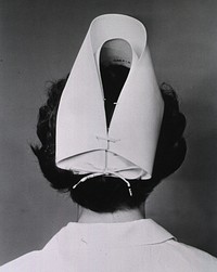 Nurse's Cap. A nurse stand with her back to the camera and is shown from the shoulders up. She models a stripeless nurse's cap. Original public domain image from Flickr