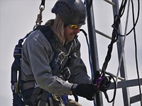 Tower Climbing Training. BLM employees participate in Tower Climbing Training. maintains about 600 antenna systems on towers or antenna support structures to provide 24/7 radio coverage for field going employees and cooperators. 6.Douglas Young latches himself to a harness. Photo by BLM. Original public domain image from Flickr