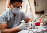 Cmdr. Yu Zhang, a maxillofacial prosthodontist prepares an acrylic dental prosthesis in hospital’s oral and maxillofacial consultation room, Naval Medical Center San Diego’s (NMCSD) Dental Department. June 11, 2021. Original public domain image from Flickr