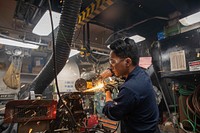 Hull Technician 3rd Class Kevin Agustin grinds metal in the general workshop aboard the Arleigh Burke-class guided-missile destroyer USS Roosevelt (DDG 80), Norwegian Sea, July 7, 2021. Original public domain image from Flickr