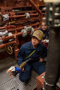 Machinist’s Mate 3rd Class Erika Birry, front, and Machinist’s Mate 3rd Class Kitiara Hunt fight a simulated fire during a damage control drill aboard the Arleigh Burke-class guided-missile destroyer USS Roosevelt (DDG 80), Arctic Sea, July 9, 2021. Original public domain image from Flickr