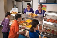School Nutrition Professionals offering school lunch to students at the serving line. Original public domain image from Flickr