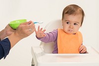 Infant is pushing away food with her hand demonstrating a sign of fullness. Original public domain image from Flickr