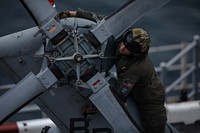 Naval Air Crewman (Helicopter) 2nd Class Conor Champagne, assigned to Helicopter Sea Combat Squadron (HSC) 28, inspects the tail rotor blade of a MH-60S Sea Hawk helicopter after landing aboard the Wasp-class amphibious assault ship USS Kearsarge (LHD 3). (U.S. Navy photo by Mass Communication Specialist Seaman Taylor Parker). Atlantic Ocean, July 30, 2021. Original public domain image from Flickr