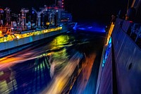 The San Antonio-class amphibious transport dock ship USS Arlington sails alongside the Henry J. Kaiser-class fleet replenishment oiler USNS Joshua Humphreys during an underway replenishment at night. Original public domain image from Flickr