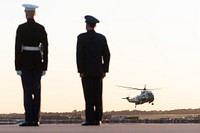 A U.S. Marine and U.S. Air Force personnel stand at attention as Vice President Kamala Harris aboard Marine Two prepares to land. Original public domain image from Flickr