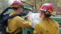Eyes on the MapTwo firefighters study a map of the Six Rivers Lightning complex. Photo Credit: CAIIMT14
