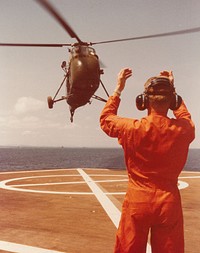 Flight deck director signals helicopter for landing on board U.S.S. Repose (AH-16). July 1966. [medical evacuation]