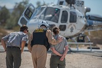 Joshua Tree Search and Rescue training with California Highway Patrol (CHP)NPS staff review helicopter safety protocol with CHP Pilot and crew. NPS / Anna Cirimele Alt Text: Two uniformed rangers are instructed by a California Highway Patrol helicopter crew member during search and rescue training for staff. A blue and white helicopter with gold striping and law enforcement star logo rests in the background.