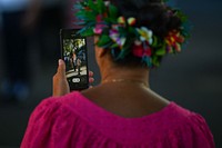 A spectator records video during a “Victory in Europe Day” World War II remembrance ceremony outside the Haut-commissariat de la République Tahiti, French Polynesia, May 8, 2022.