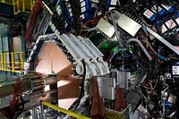 The STAR detector at the Relativistic Heavy Ion Collider shows endcap calorimeter electronics (blue with black cables) and four new planes of small-strip Thin Gap Chambers (copper colored with white at edges) during insertion into the detector at Brookhaven National Laboratory. 