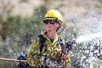 MAY 15: Female firefighter with hoseKINGMAN, AZ - MAY 15: A female Kingman district wildland firefighter deploys a hose to fight a mock fire in the desert east of Kingman, Arizona. The exercise was part of the 2022 Arizona Fire Preparedness Review in Kingman, Arizona on Sunday, May 15, 2022. Photo by Suzanne Allman, contract photographer for BLM